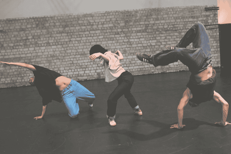 Drei Tänzer*innen performen im Stil von Break Dance