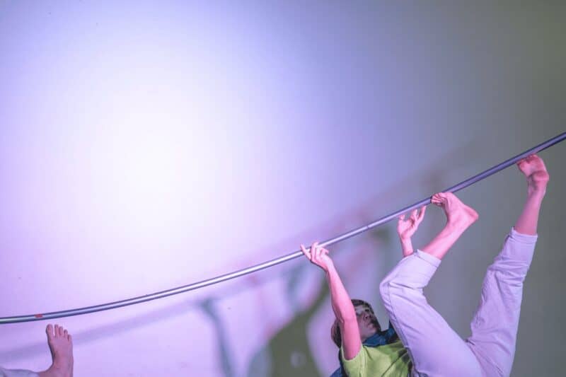 An einem runden Stab sieht man unten eine Tänzerin